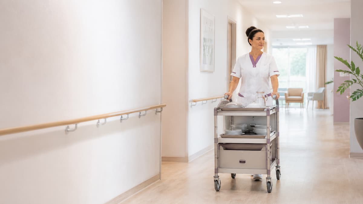 Soignante déplaçant un chariot dans un couloir d’EHPAD, situation de travail à analyser pour prévenir les TMS liés aux efforts de poussée et de traction.